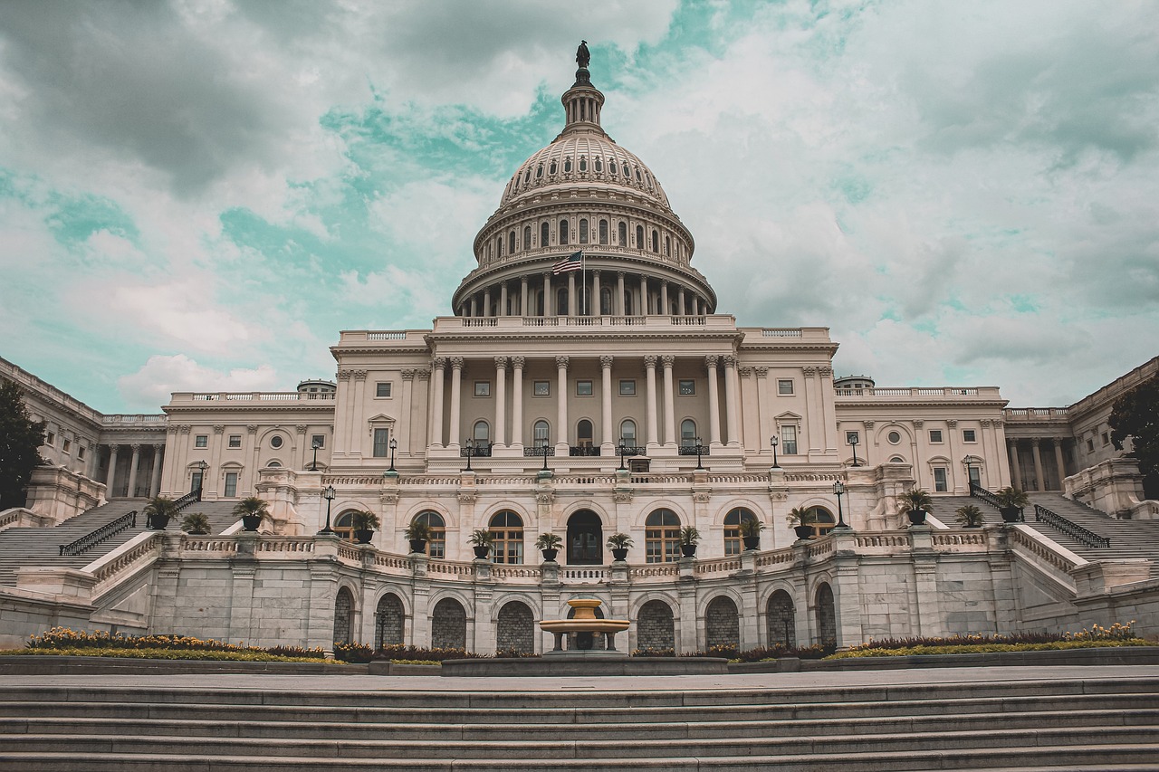 A wide-angle, symmetrical view of the United States Capitol building under a cloudy sky.